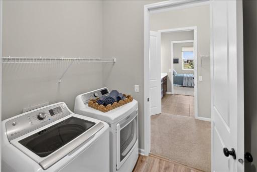 Conveniently located laundry room with washer, dryer, and additional shelving to simplify everyday living.