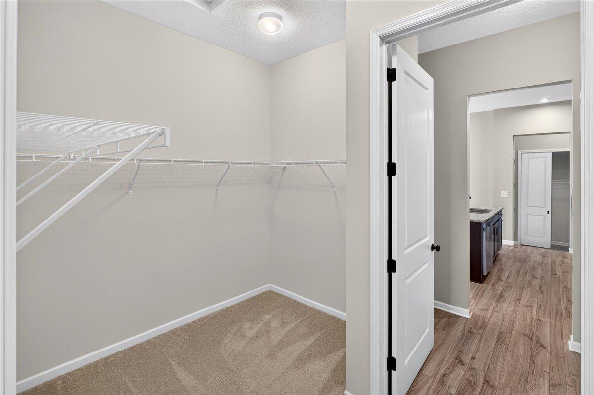 Generously sized closet with hanging space and shelving, conveniently located near the primary bathroom. Plenty of room to organize clothing, shoes, and accessories in the primary suite's walk-in closet.
