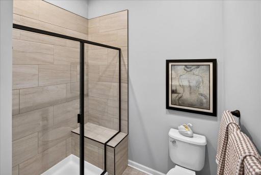 Beautifully tiled shower with glass enclosure, built-in bench, and modern finishes.