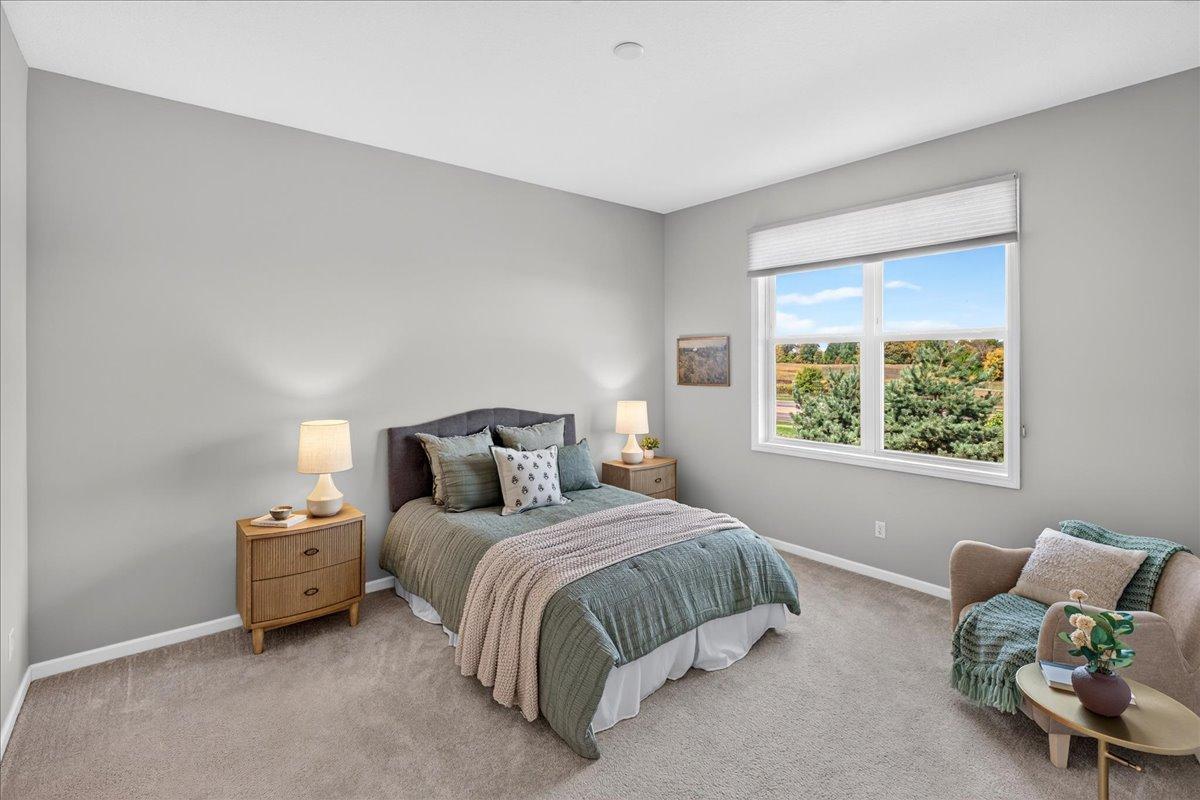 A spacious, relaxing retreat with neutral finishes, soft carpeting, and a large window bringing in natural light.