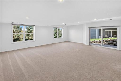 Large windows and a walkout patio door brighten the lower-level family room, creating an inviting extension of the home.