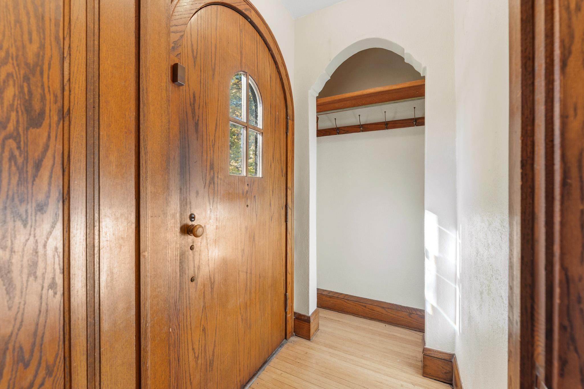Original solid wood arched front door and coat closet in front entry