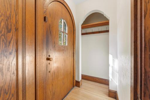 Original solid wood arched front door and coat closet in front entry