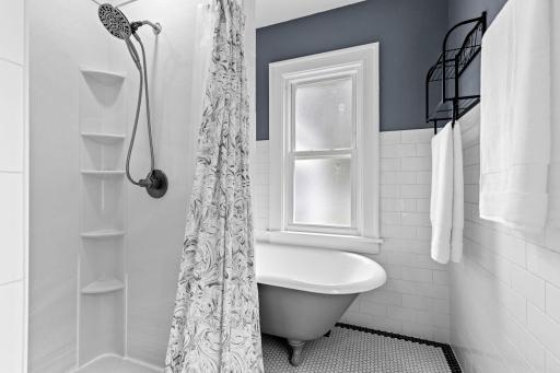 Complete with a Bath Fitter shower, standalone tub, tile detailing, and a Bluetooth-enabled vent fan with built-in speaker.