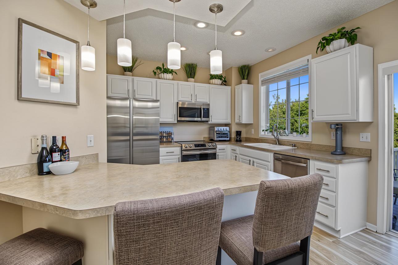 Kitchen has wonderful updates with stainless steel appliances, pendant lights, white cabinets, and great view of the golf course!