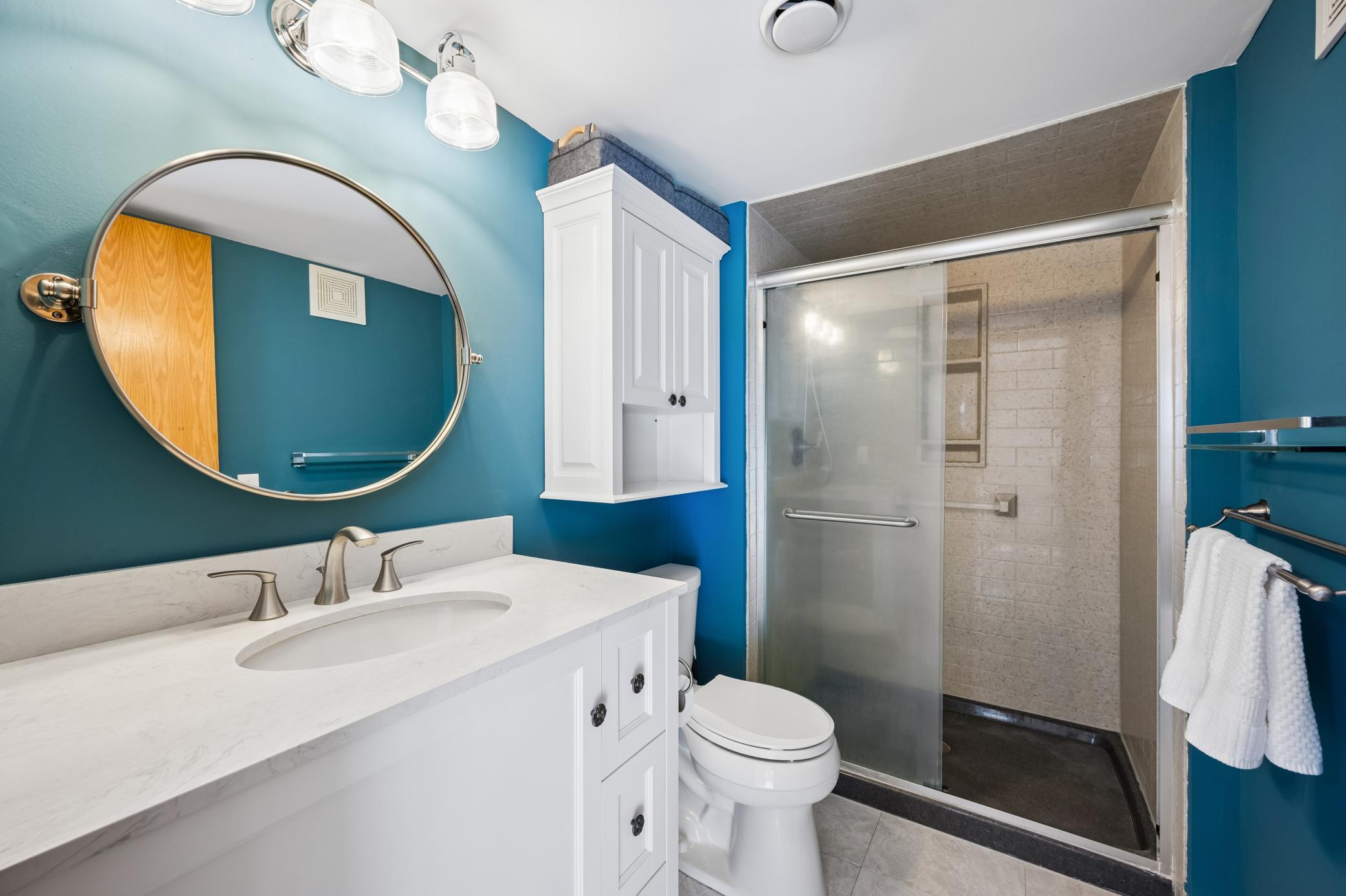 Updated lower level 3/4 bathroom with tiled shower, updated vanity, light fixtures, flooring and mirror.
