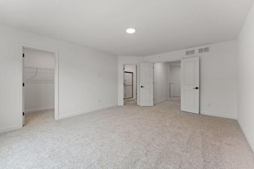 (Photo of a similar home, actual finishes may vary) The primary bedroom embraces natural light streaming in from the large windows
