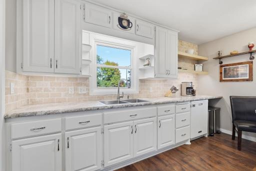 Remodeled kitchen features bright white cabinets and a large window over the sink.