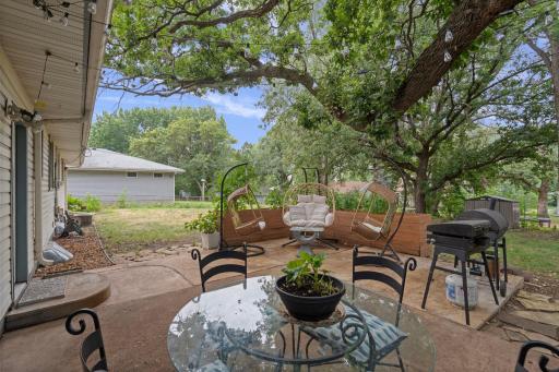 Extended concrete patio leads to a charming backyard retreat made for summer nights under the trees!
