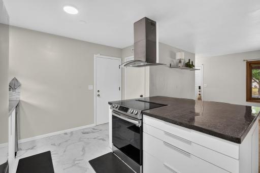 Spacious kitchen island with cooktop and statement range hood.