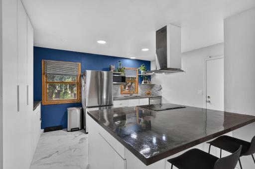Modern kitchen featuring gleaming concrete countertops, stainless steel appliances(2025), and a large center island with storage.