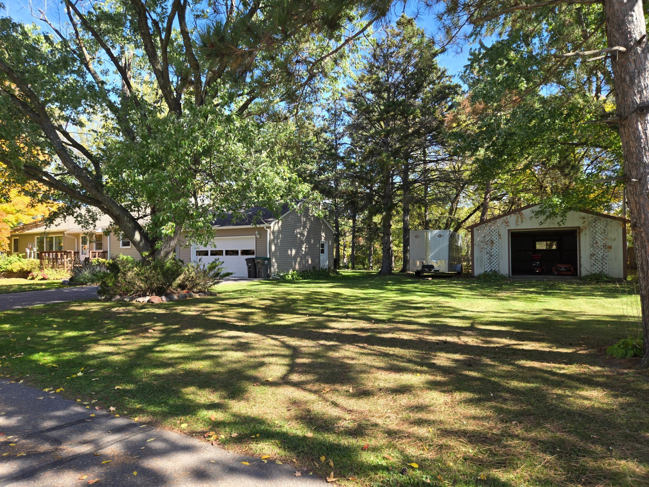 Beautiful, tree-lined yard with mature trees, generous green space, and a detached pole building offering endless possibilities for storage and hobbies.