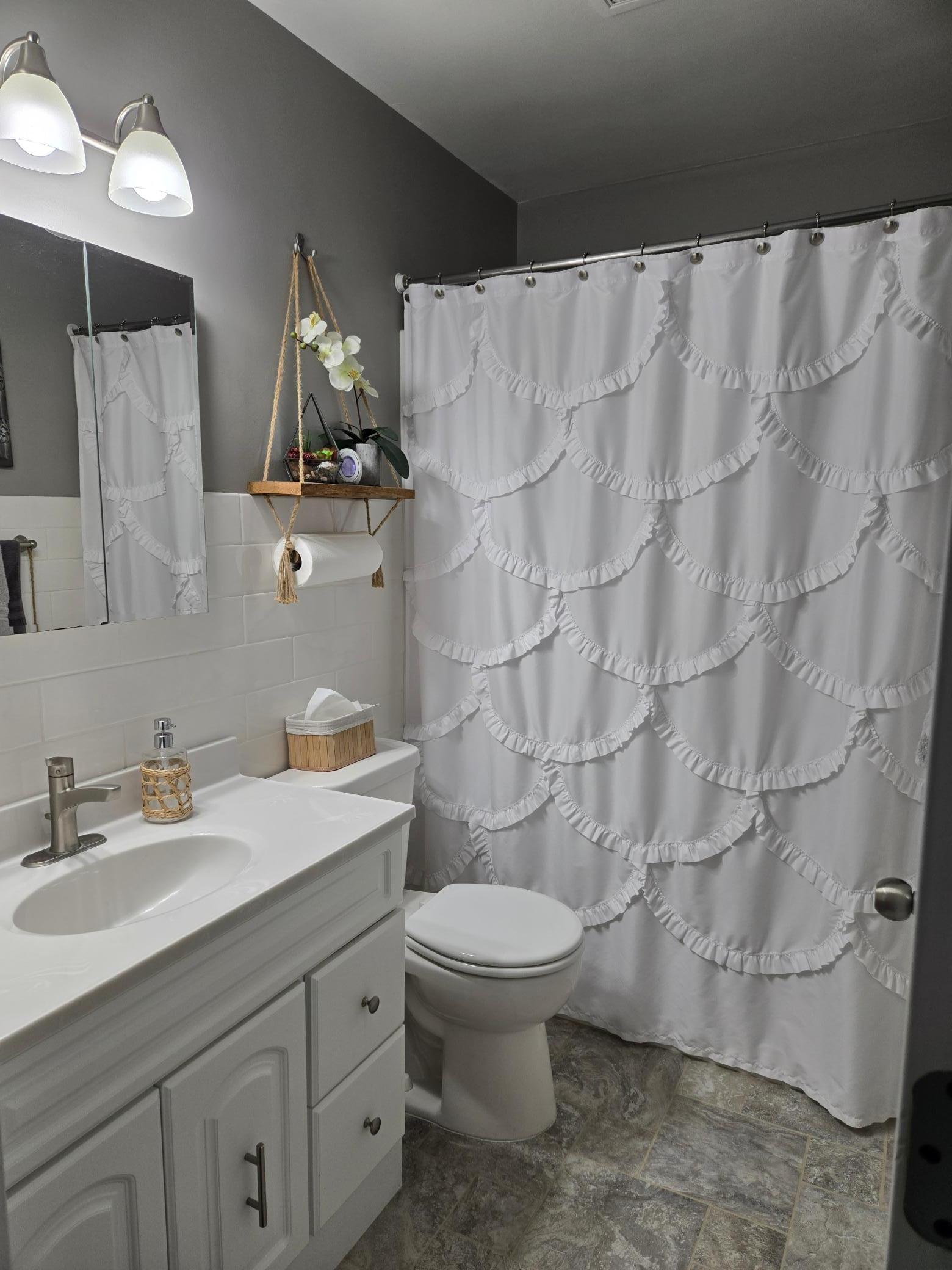 Updated main-level full bathroom featuring a white vanity, modern fixtures, attractive tile flooring, and a tub/shower combination with classic white tile surround.