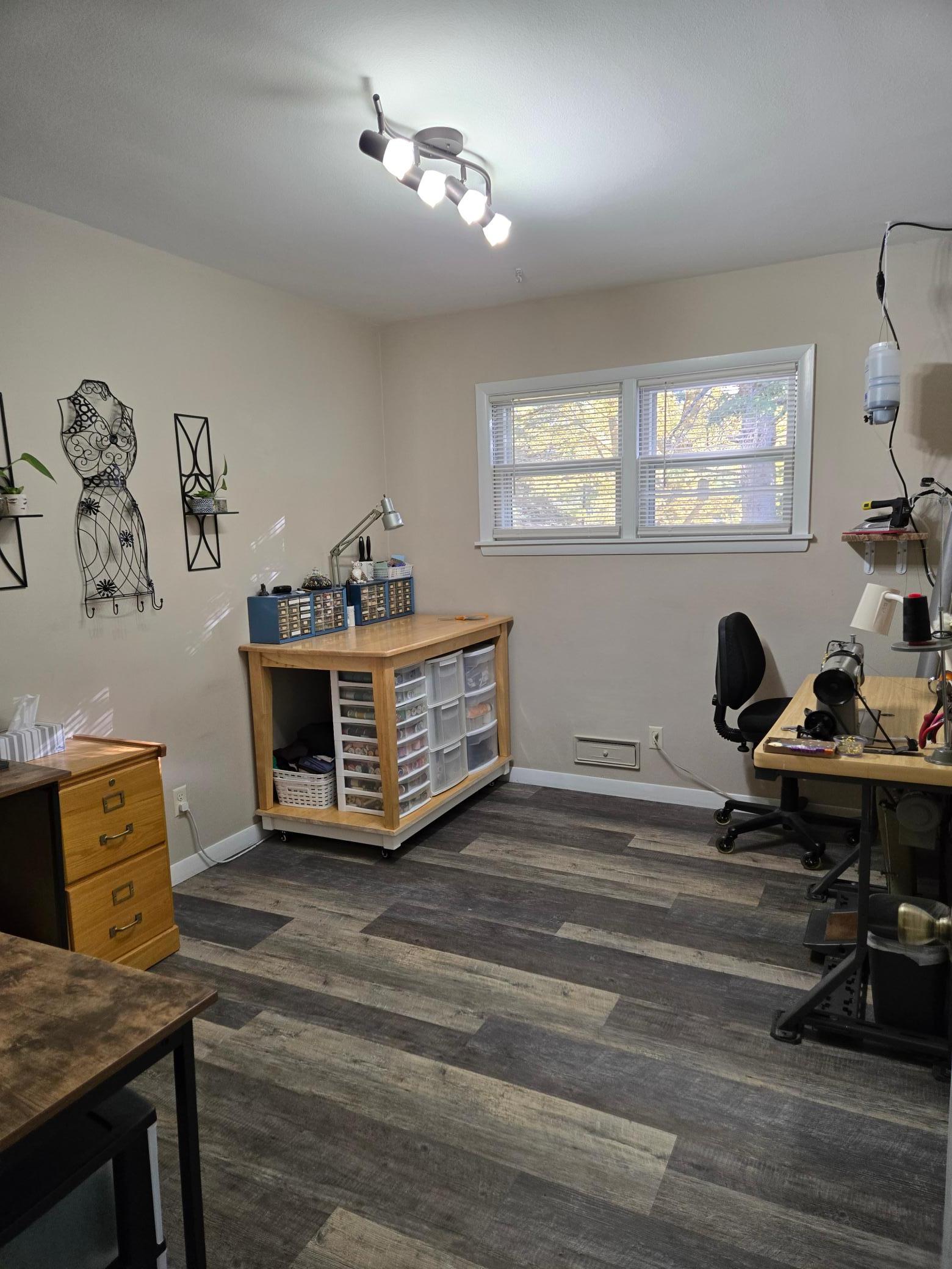 Versatile main-level room featuring updated flooring, a large window, and plenty of space for a home office, hobby room, craft room, or additional bedroom.