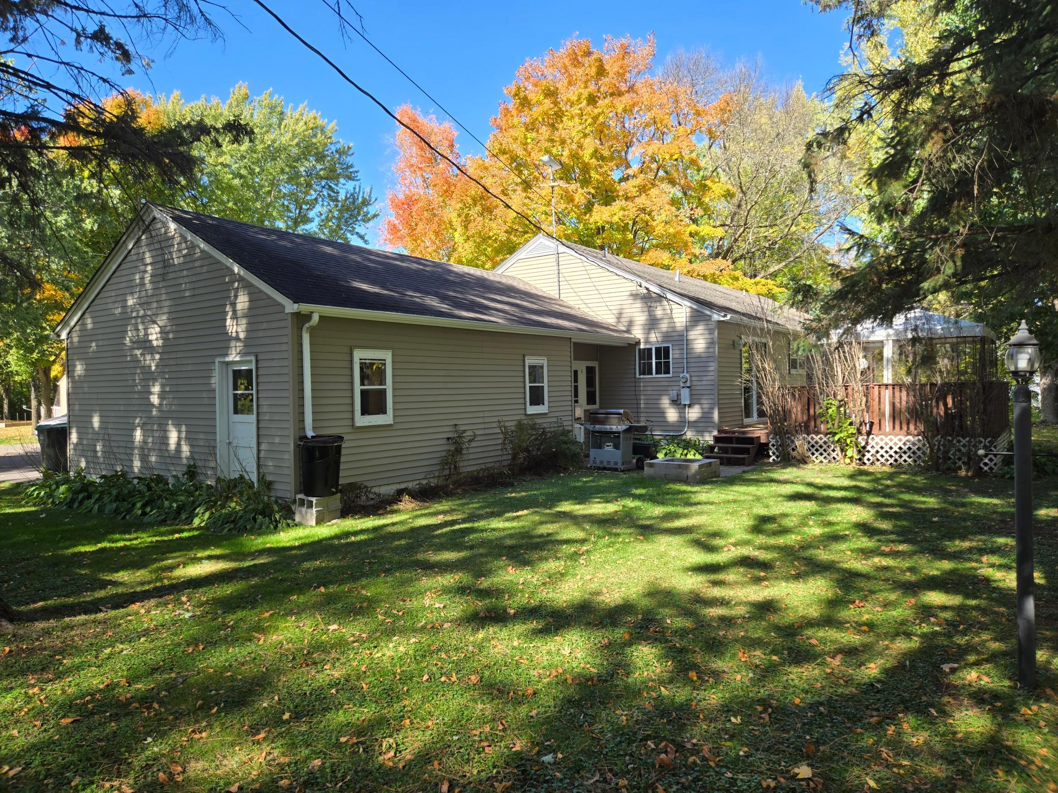 Inviting backyard featuring a deck, established landscaping, and beautiful mature trees that provide a lovely setting for outdoor entertaining.