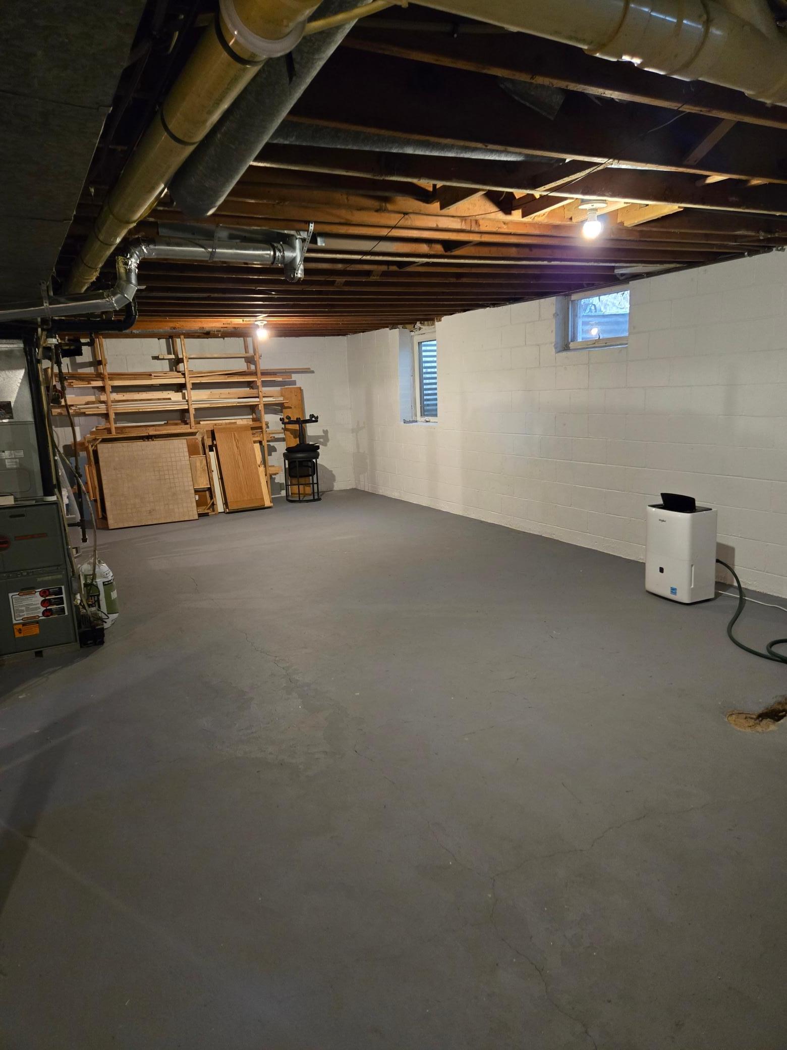 Additional view of the expansive unfinished lower level, featuring plenty of workspace and room for storage or recreational equipment.