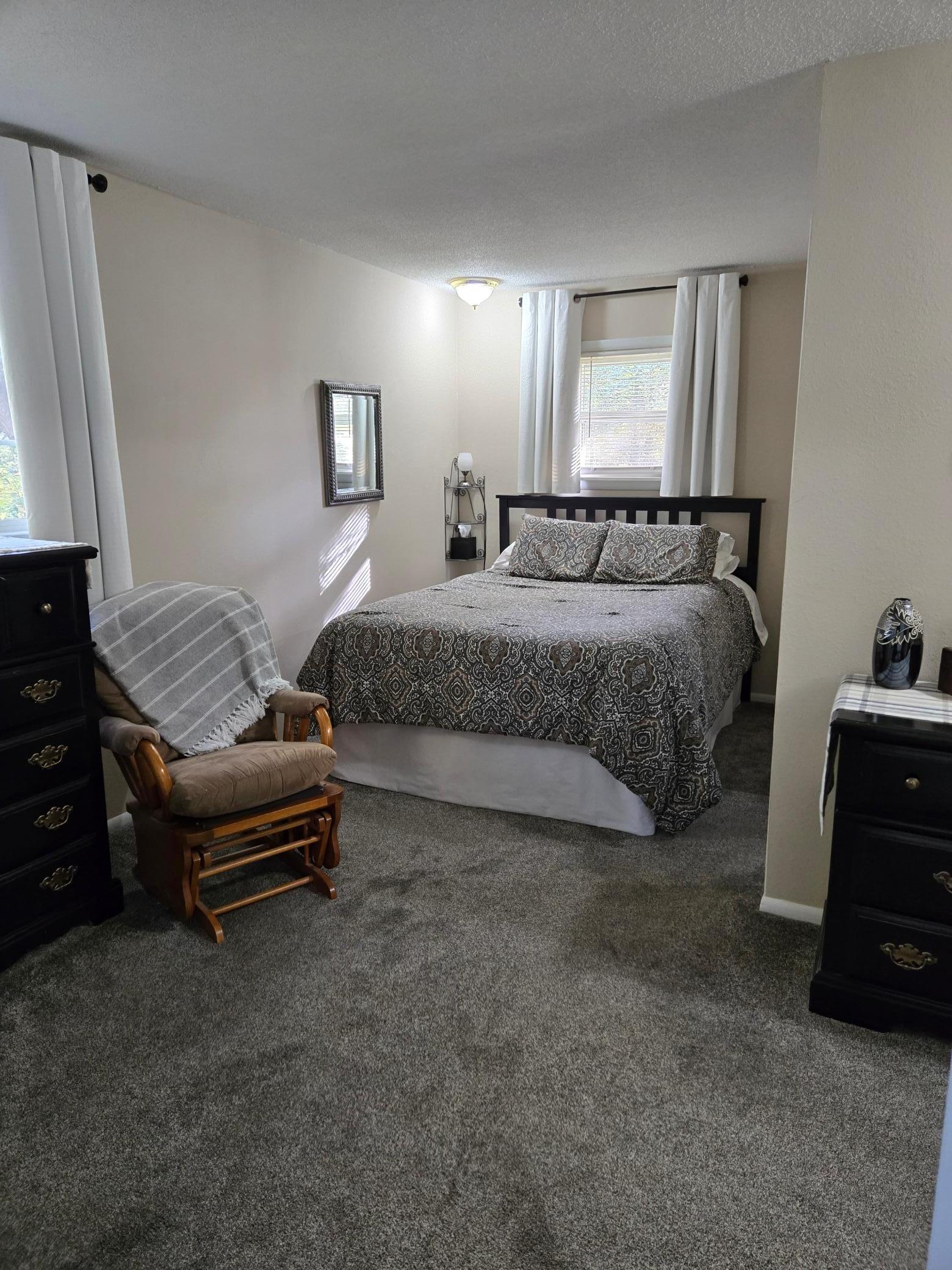 Spacious primary bedroom suite featuring neutral tones and convenient access to an exceptionally large walk-in closet and private half bath.