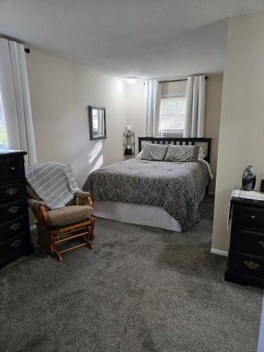 Spacious primary bedroom suite featuring neutral tones and convenient access to an exceptionally large walk-in closet and private half bath.