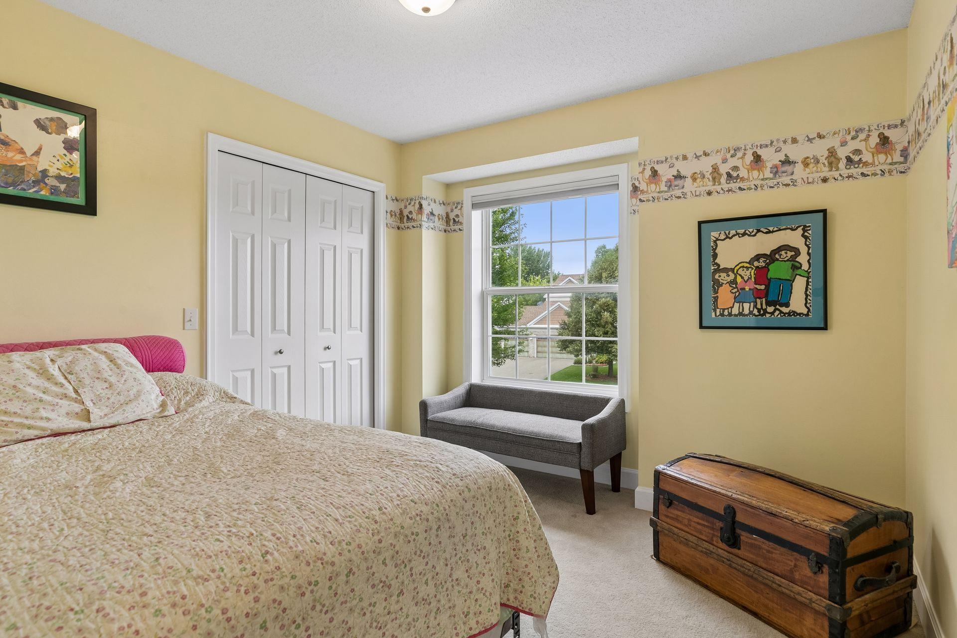 The first of three upper level bedrooms provides a generous layout with carpet flooring, an oversized window, walk in closet, and overhead lighting.