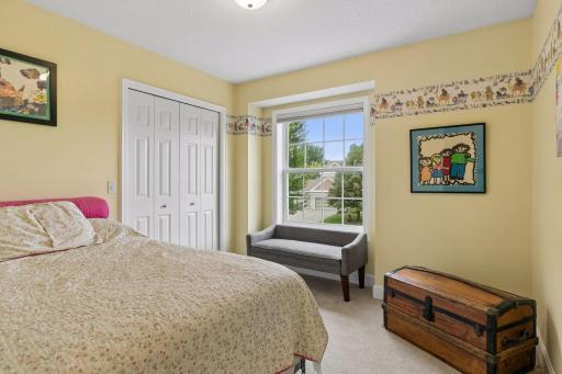 The first of three upper level bedrooms provides a generous layout with carpet flooring, an oversized window, walk in closet, and overhead lighting.
