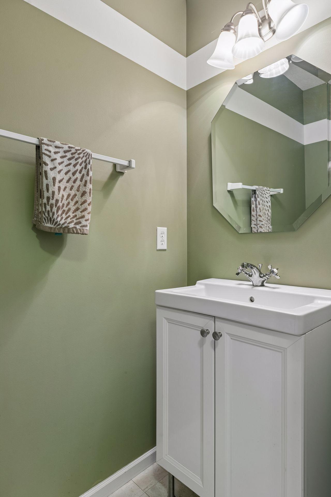 A nicely appointed half bath on the main level offers LVT flooring, a vanity sink, mirror, and stylish wall lighting.