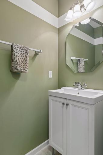 A nicely appointed half bath on the main level offers LVT flooring, a vanity sink, mirror, and stylish wall lighting.