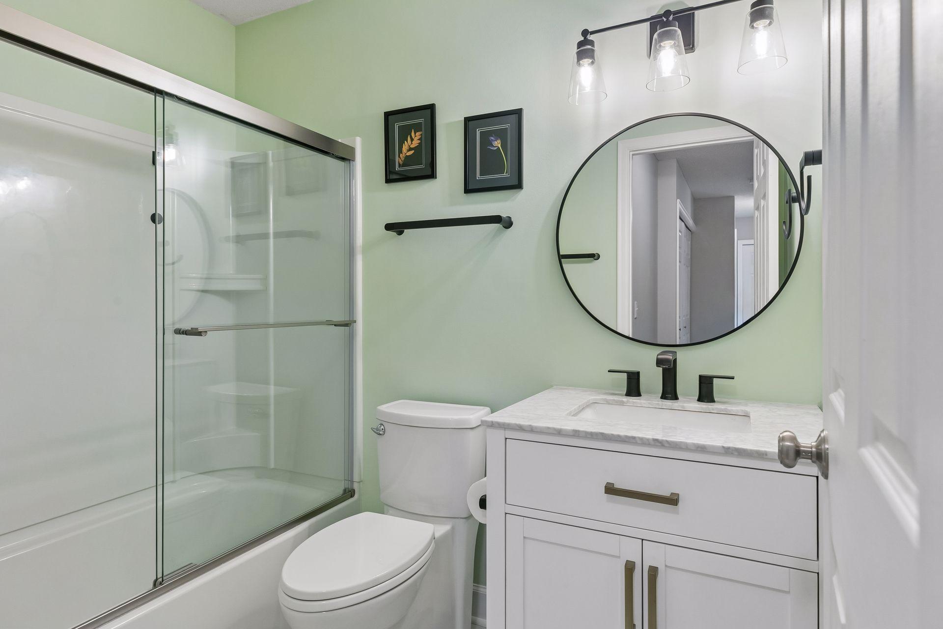 The updated (2023) upper level bathroom combines style and function with LVP flooring, a vanity, mirror with wall lights, and tub/shower combination.