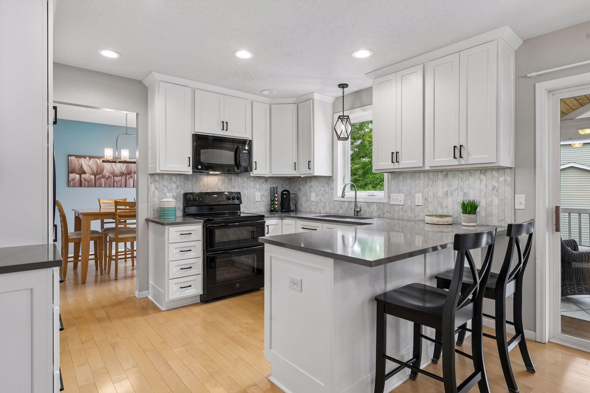 Custom cabinetry, quartz countertops, recessed lights, abundant workspace, and a breakfast bar come together in this beautifully renovated kitchen.