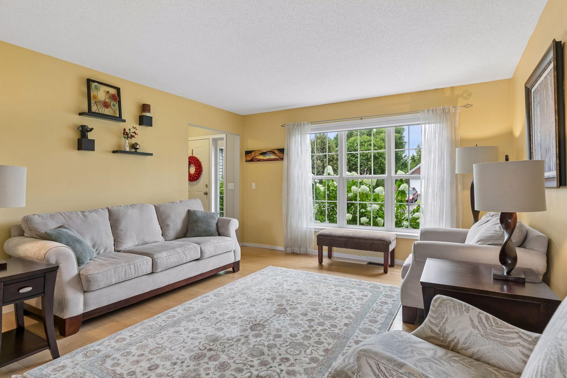 Natural light pours through a large picture window, complementing the spacious layout and creating an inviting setting for entertaining or relaxing.