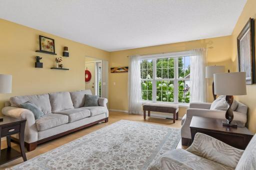 Natural light pours through a large picture window, complementing the spacious layout and creating an inviting setting for entertaining or relaxing.