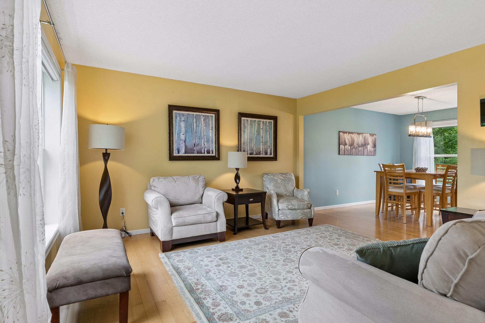 The maple hardwood flooring extends through the living room, creating a seamless connection to the adjacent formal dining room.