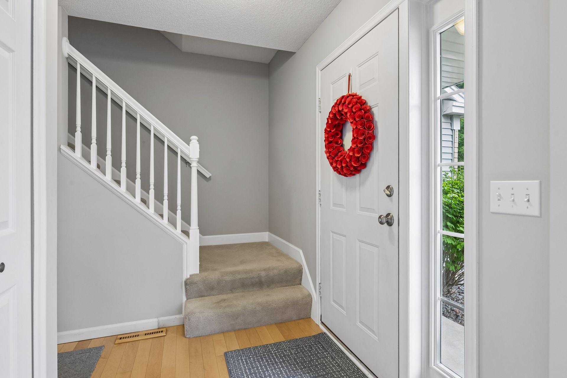 Warm maple hardwood flooring sets the tone in the foyer, complemented by a coat closet, overhead lighting, and access to the upper level.