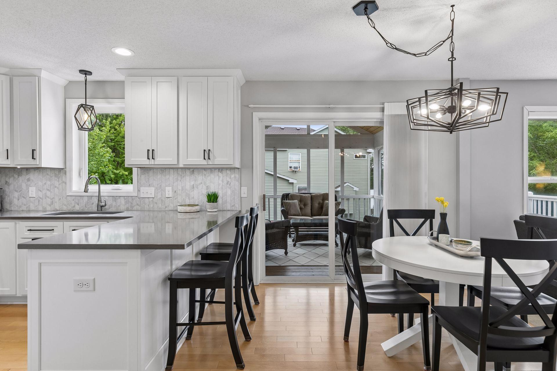 The informal dining space connects effortlessly to the outdoors with continued hardwood flooring, stylish chandelier lighting, and sliding door access to the screened porch and deck.
