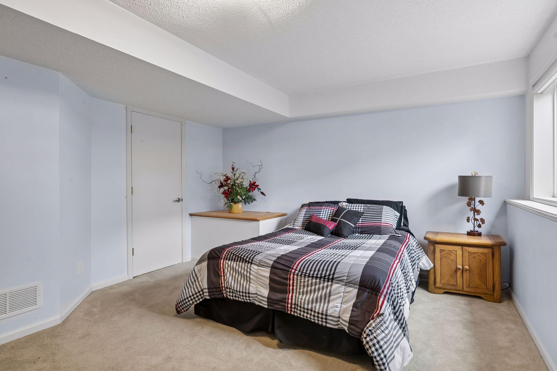 The lower level bedroom provides a comfortable and private space with carpet flooring, a walk in closet, overhead light and a bright double window.