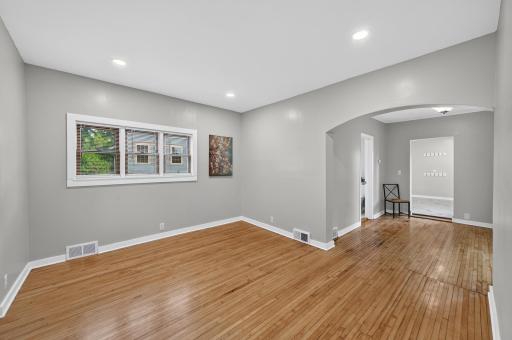 Entrance opens to living room. Beautiful arch entryway to dining room and original hardwood flooring.