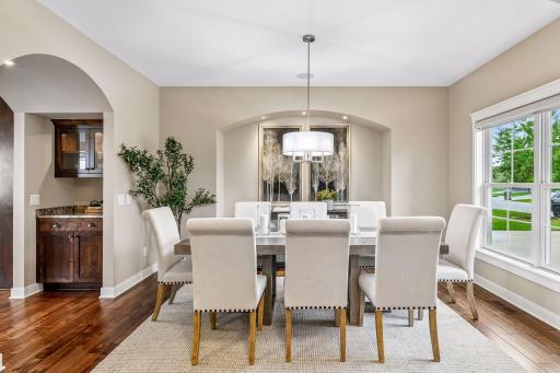Spacious dining room framed by graceful arched architectural details and warm hardwood floors.