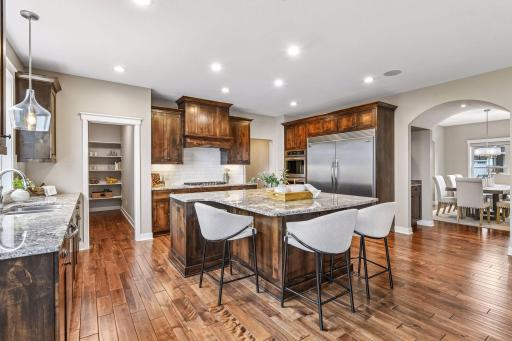 A spacious chef's kitchen pairs rich alder cabinetry with expansive stone countertops, a generous center island with seating, and an easy flow into adjoining informal dining area and great room.