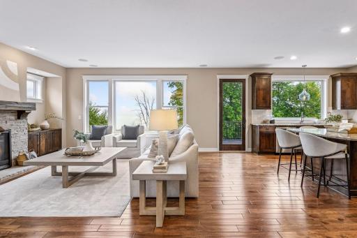 Great room with stunning hardwood floors, oversized windows, and a stone-surround gas fireplace with custom built-ins.