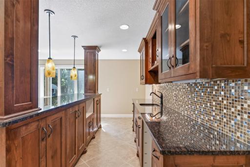 A detailed tile backsplash and under-cabinet lighting add another layer of refinement and ambiance to this impressive entertaining space.