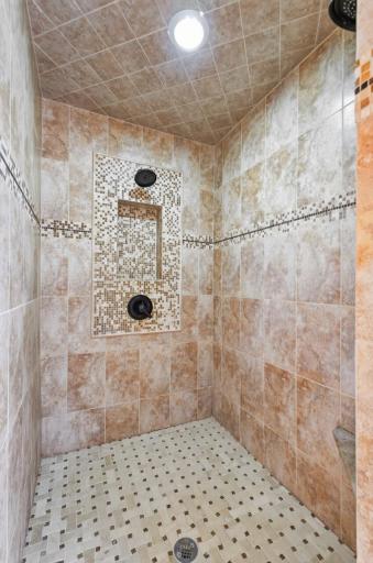 A generously sized, beautifully tiled walk-in shower creates a spa-like experience and brings an elevated sense of luxury to the primary bath.
