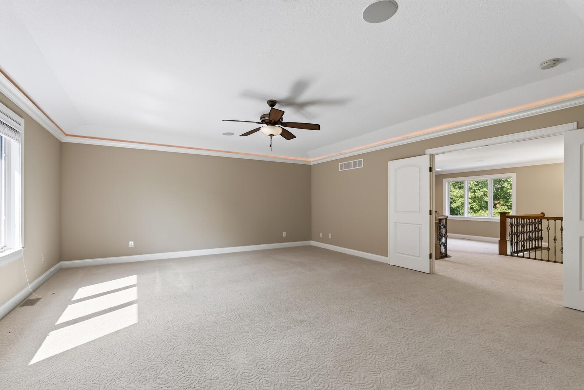 Cove lighting beautifully accentuates the primary suite’s tray-vaulted ceiling, while a ceiling fan adds everyday comfort to this spacious and serene retreat.