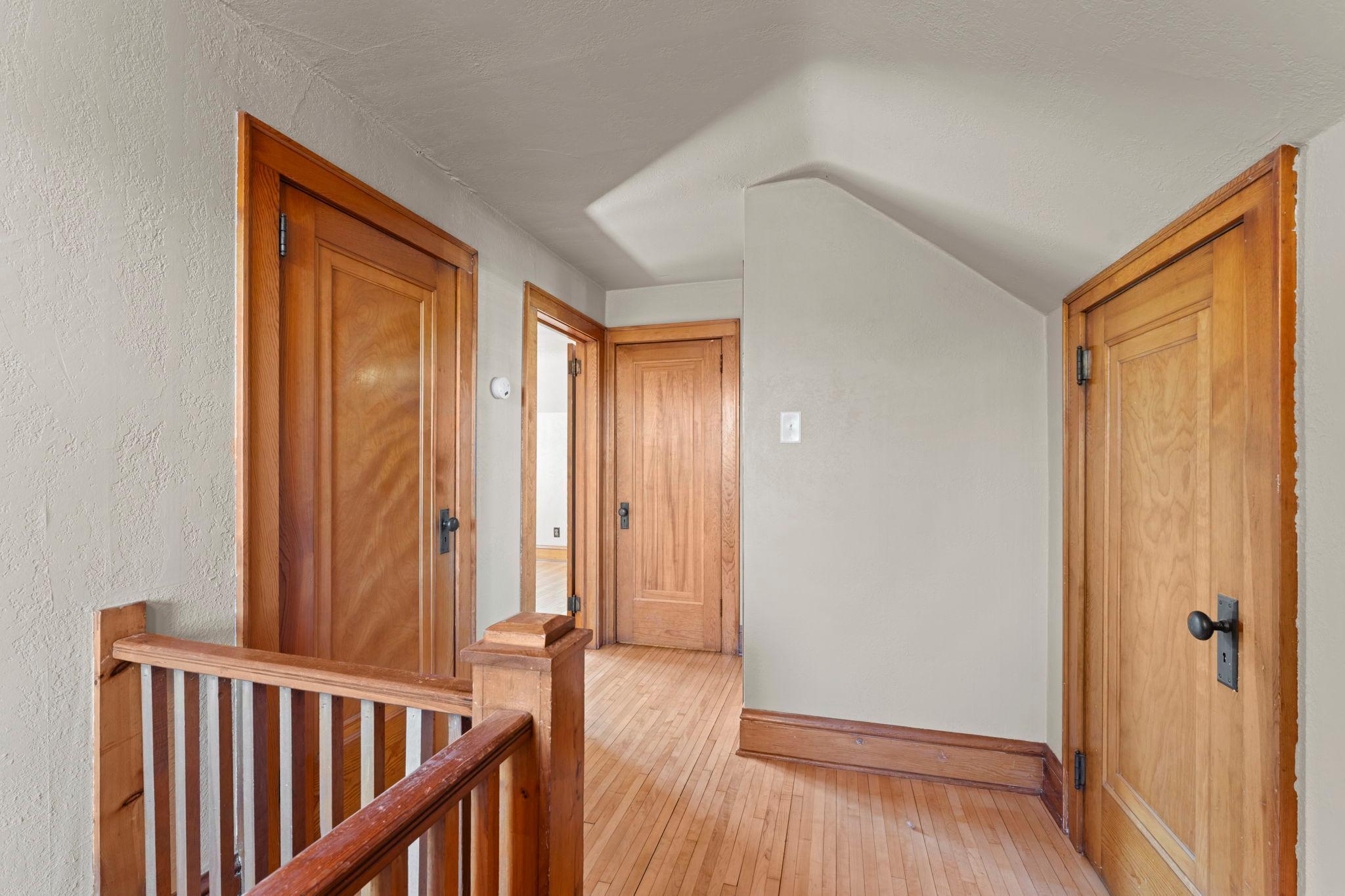 Hallway showing doors to attic spaces, bedrooms and bathroom