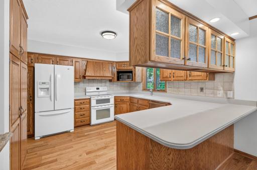The light and bright kitchen has gorgeous corian counters, quality craftsmanship, a beautiful tile-surround backsplash, and loads of cabinet and counter space.