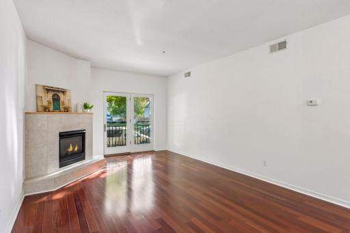 Bright living room featuring a gas fireplace with tile surround and mantel, adding a comfortable focal point to the open living space. Exterior-style glass door brings in natural light and can be opened for fresh air.