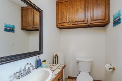 Main-floor half bath includes overhead cabinetry for tucked-away storage.