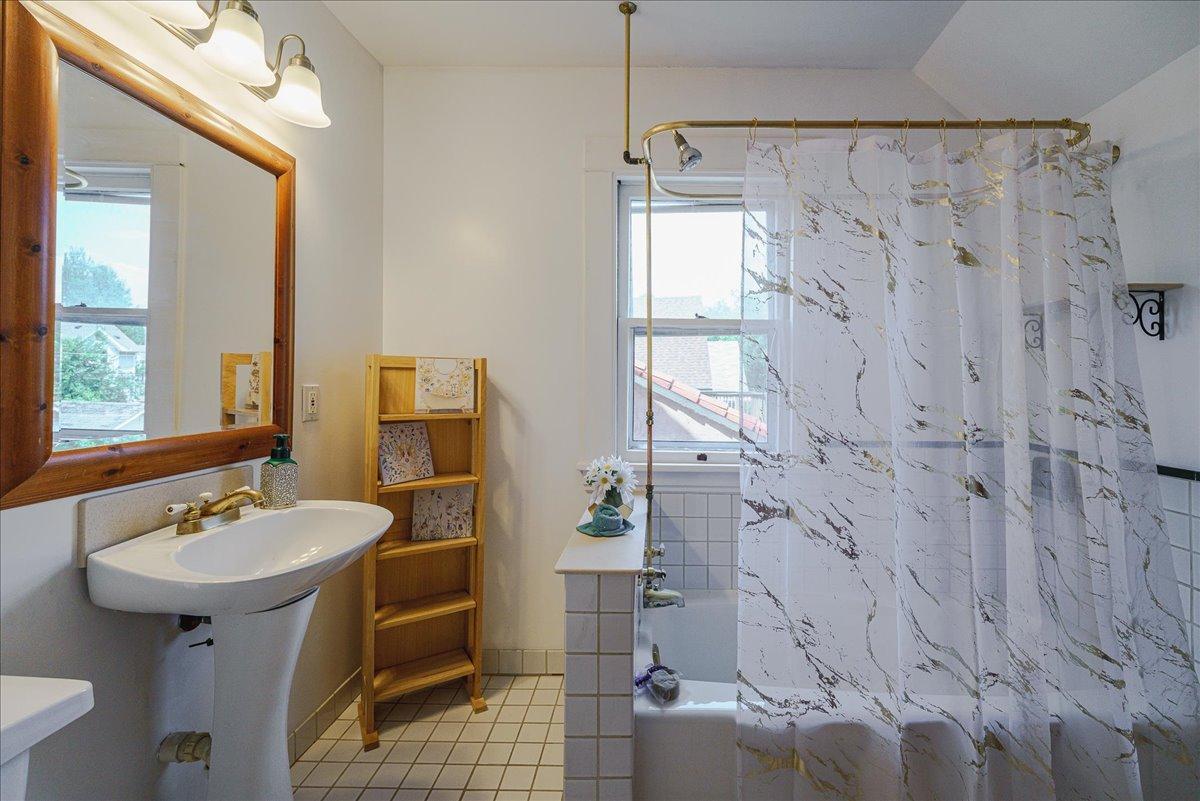Charming upper-level full bathroom with a pedestal sink and shower/tub combo.