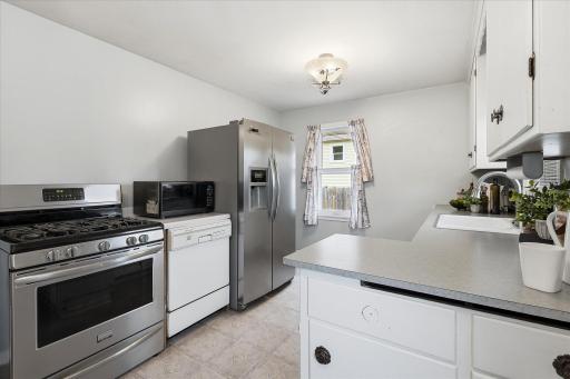Stainless steel gas range and refrigerator, ample workspace, and functional layout.