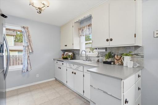 Kitchen features abundant cabinetry, generous counter space, and a decorative tile backsplash with accent detailing.
