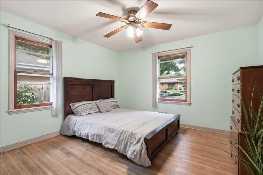 Main-level bedroom features hardwood floors, multiple windows for natural light, and a ceiling fan.