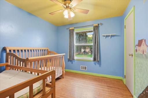 Main-level bedroom #2 features hardwood floors, and a ceiling fan.